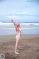 A woman in a white bikini standing on a beach.