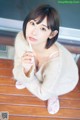 A woman sitting on a wooden floor holding a toothbrush.