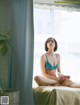 A woman in a blue bikini sitting on a bed.