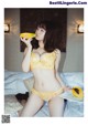 A woman in a yellow lingerie eating a papaya.