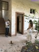 A man taking a picture of a woman standing in front of a building.