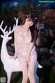 A woman in a white lingerie posing next to a white deer.