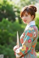 A woman in a colorful dress holding a fan.