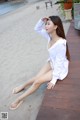 A woman sitting on a wooden walkway next to a beach.