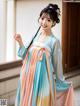 A woman in a blue and orange hanbok is posing for a picture.