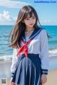 A woman in a school uniform standing on a beach.