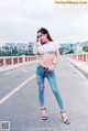 A woman in ripped jeans and a white t-shirt posing on a bridge.