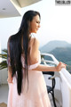 A woman in a pink dress standing on a balcony.