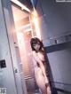 A naked woman standing in a room next to a door.