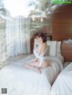 A woman sitting on a bed in a white lingerie.