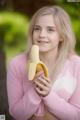 A young woman holding a banana in her hands.